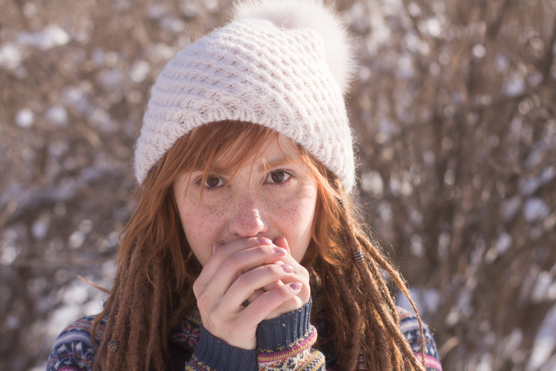 Vrouw met een gebreide muts die zich warm houdt in de winterse herfstomgeving.